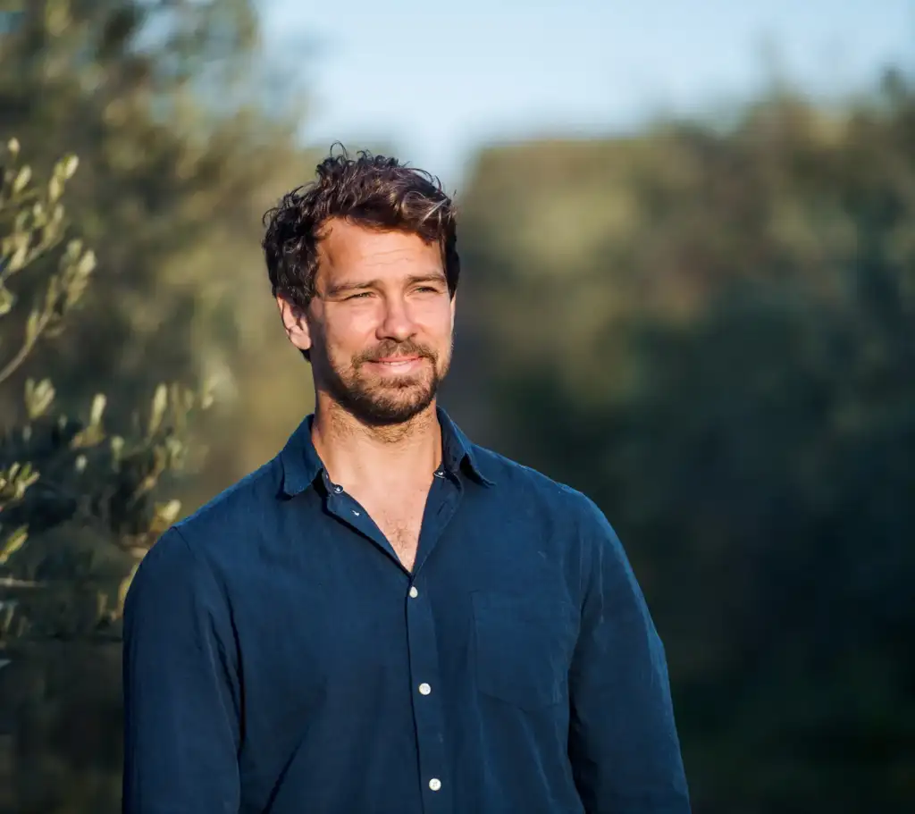 Man standing outdoors in natural light, looking off thoughtfully, suggesting reflection and clarity